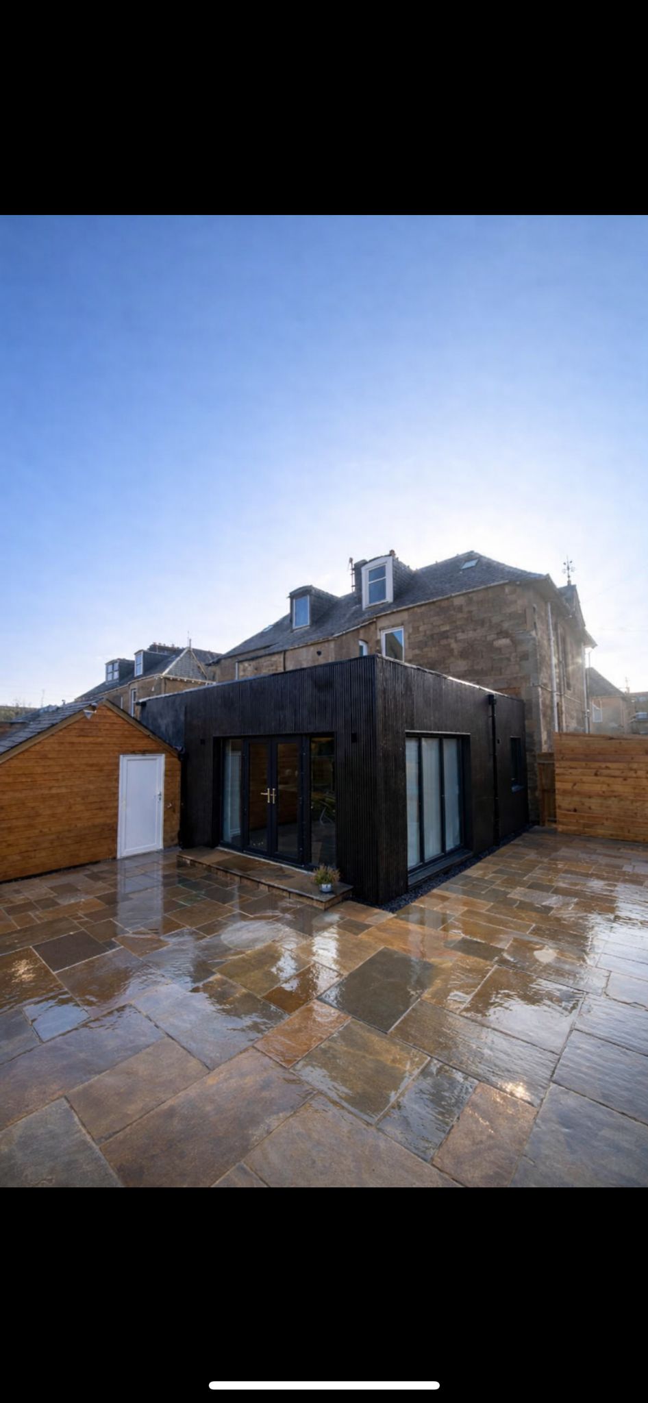 Completed rear extension with charred timber cladding, bi-fold doors and sandstone patio