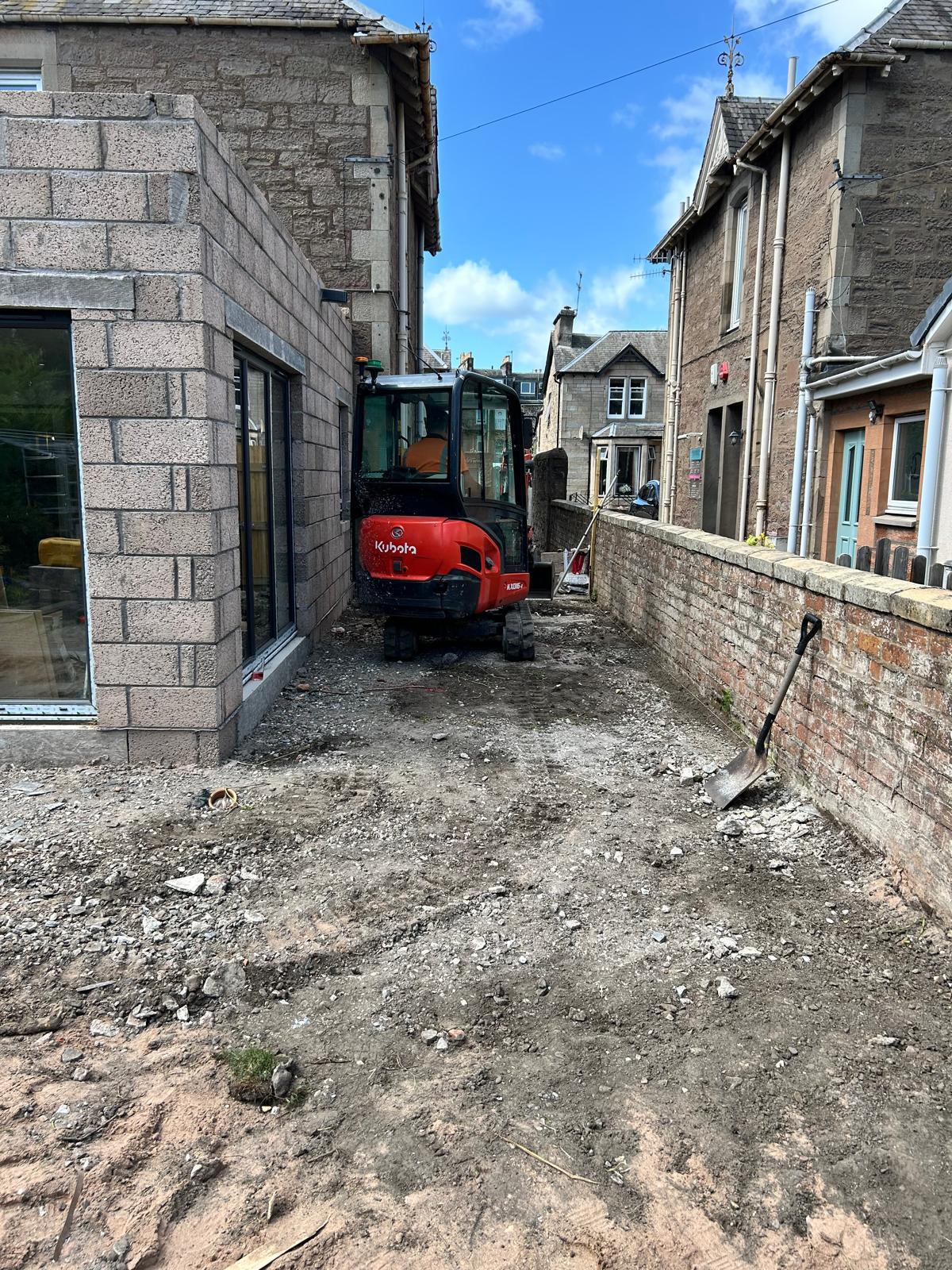 Mini excavator on residential site preparation with block work extension