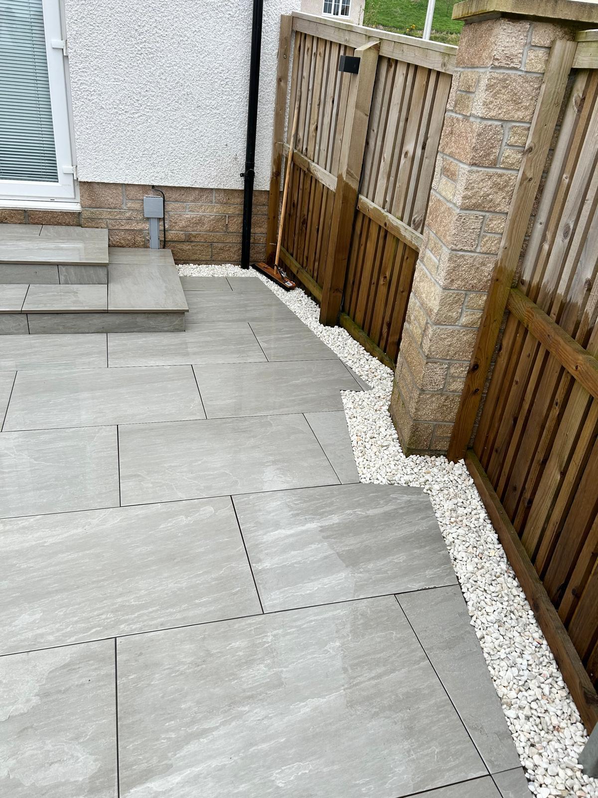 Porcelain patio with integrated stone steps leading to garden