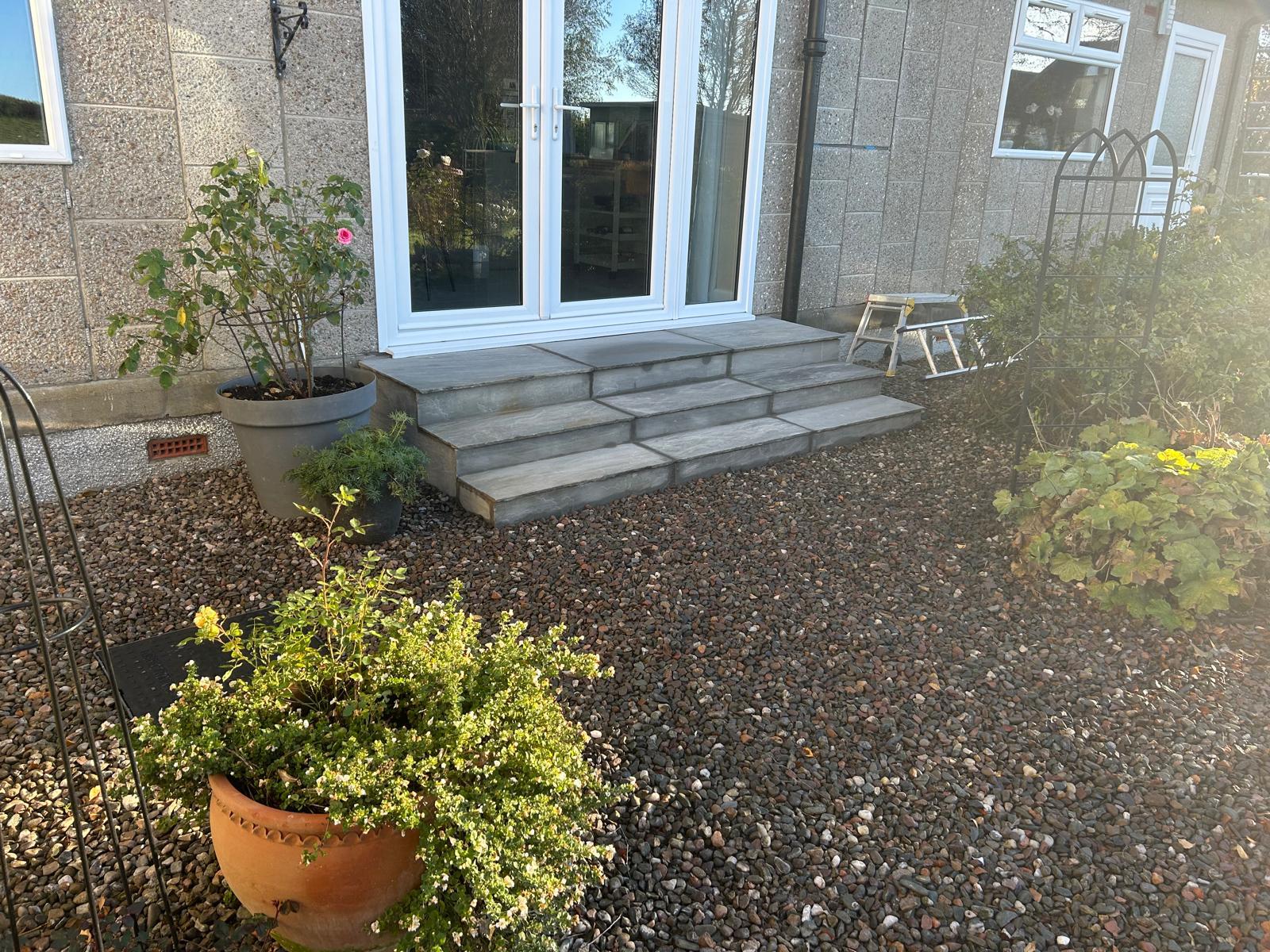 Curved stone steps with matching paved landing and planted borders