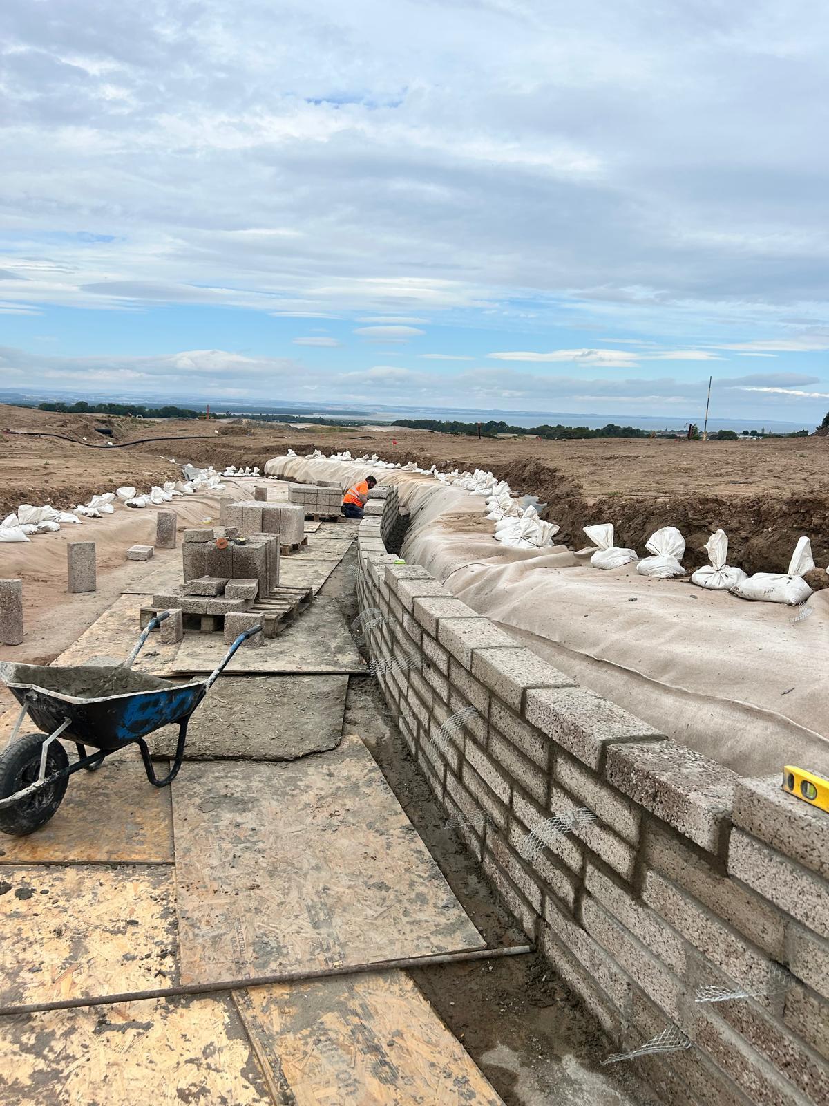 Curved block retaining wall with geotextile backing on development site