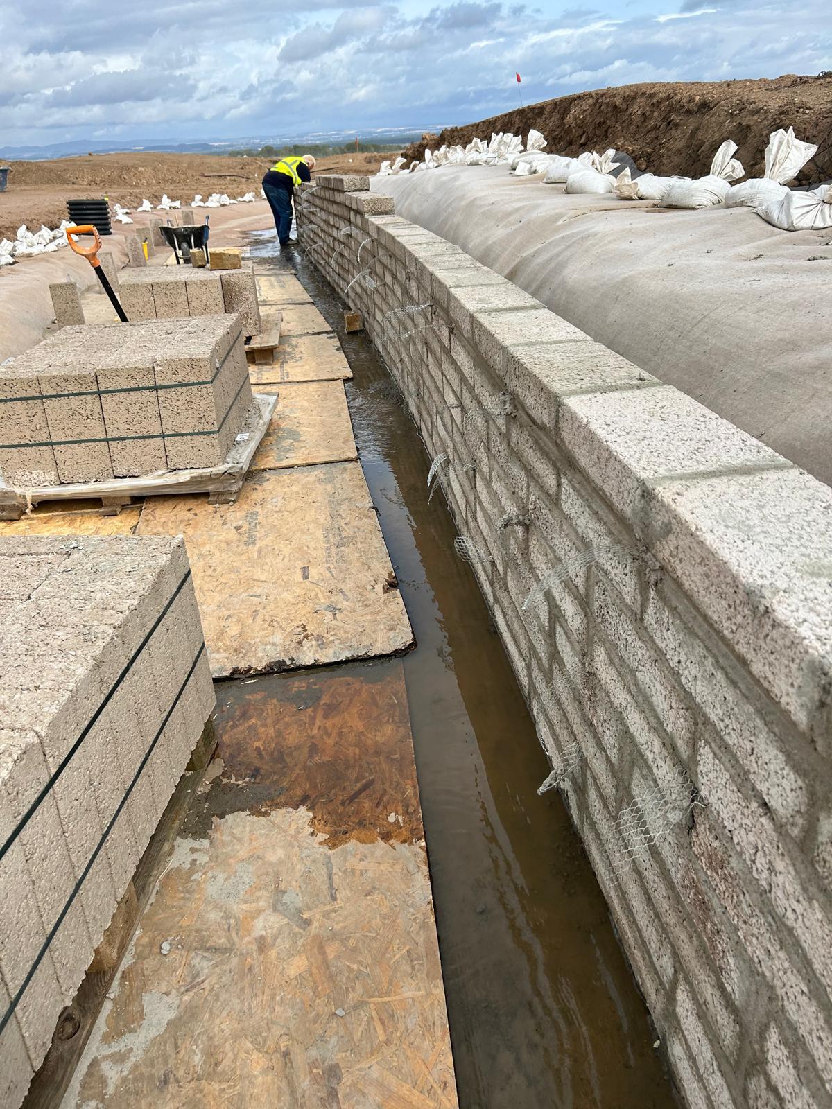 Block retaining wall with drainage channel at base, development site